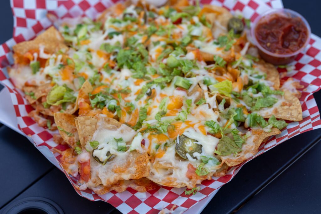 Nachos topped with melted cheese, lettuce and diced vegetables