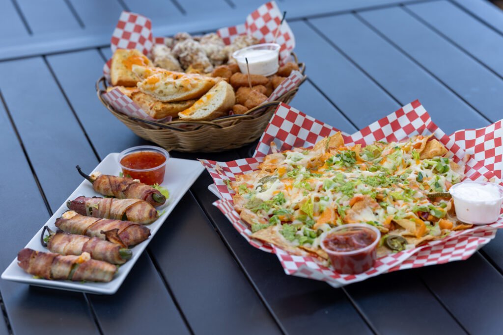 Appetizer platter, nachos and poppers arranged on a patio table