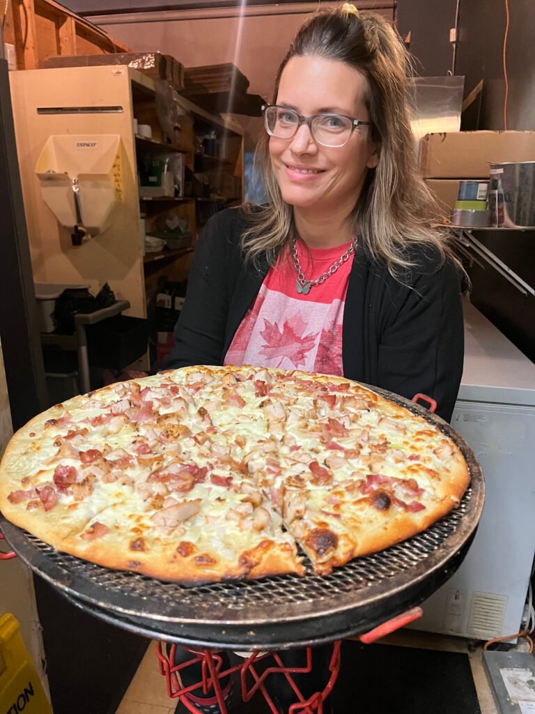 Woman holding a large pizza inside the pub